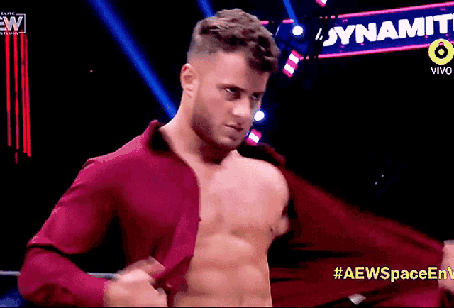 a shirtless wrestler is standing in front of a dynamite sign