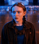 a girl with braids is standing in a dark room .