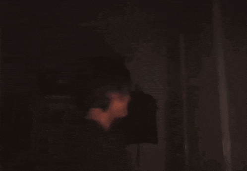 a blurry picture of a man standing in a dark room looking at something .