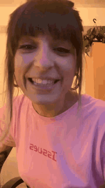 a woman wearing a pink t-shirt is smiling .