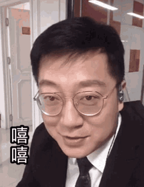 a man in a suit and tie is wearing glasses and earbuds .