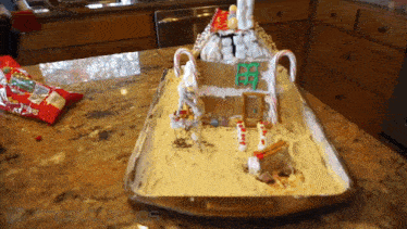 a gingerbread house is sitting on a tray with candy canes