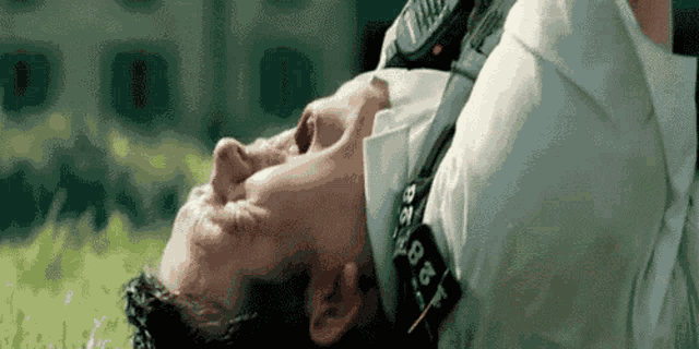 a man in a white shirt and tie is laying on his back with a cell phone around his neck .