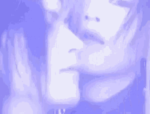 a close up of a man and woman 's faces in a purple light .