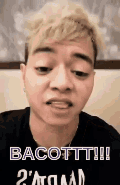 a man with blonde hair is wearing a black shirt that says bacott !!