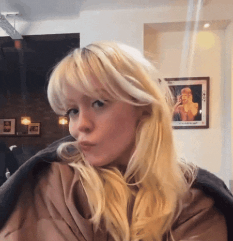 a blonde woman with a picture of taylor swift on the wall