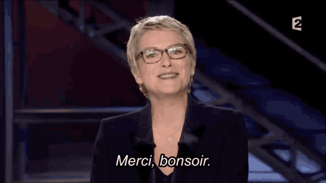a woman wearing glasses says merci bonsoir on a television screen