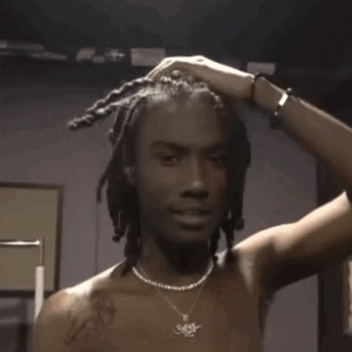 a man with dreadlocks is standing in a boxing ring without a shirt .