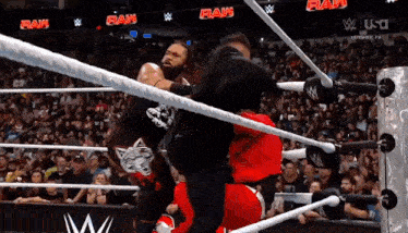 two men are wrestling in a ring with a crowd watching and a sign that says raw