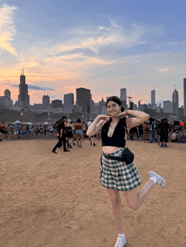 a woman in a plaid skirt stands on one leg in front of a crowd of people