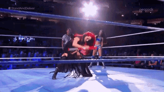 two women are wrestling in a wrestling ring with a referee in the background .