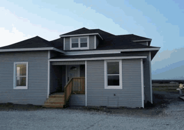 a gray house with a black roof and stairs