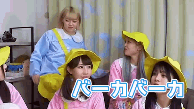 a group of young girls are sitting on a couch wearing yellow hats and aprons .