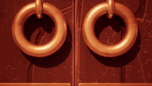 a pair of gold rings on a red surface