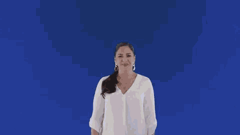 a woman in a white shirt is dancing in front of a blue background with the word ja written on it .