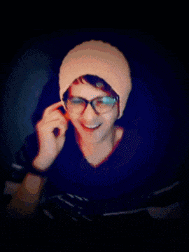 a man wearing a beanie and glasses is talking on a cell phone and the words yuhuuu are behind him
