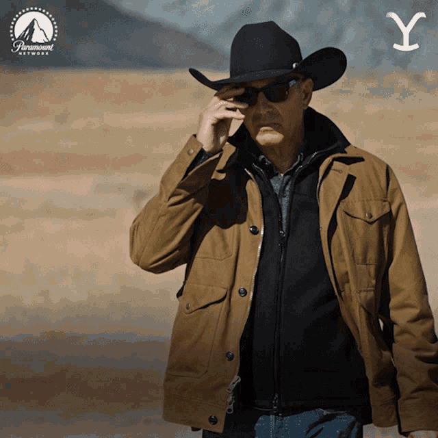 John Dutton, da série Yellowstone, tirando os óculos escuros enquanto caminha.