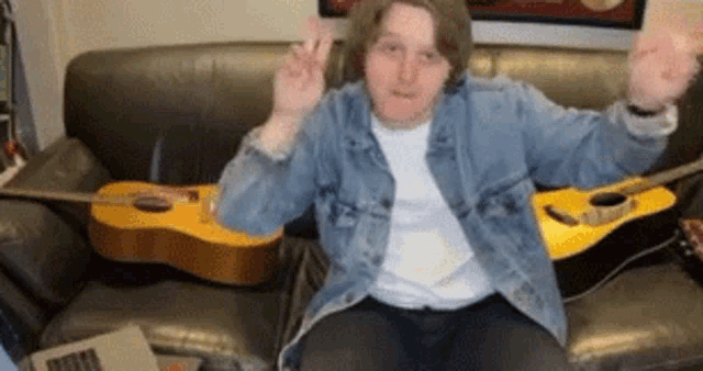 a man is sitting on a couch with a guitar in front of him .