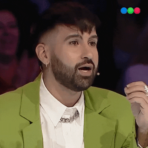 a man with a beard wearing a green jacket and white shirt