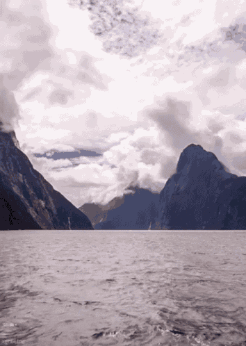 a large body of water with mountains in the background and a cloudy sky