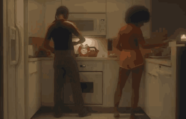 a man and a woman dancing in a kitchen with a clock on the stove