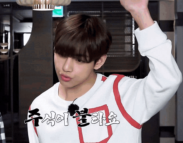 a young man wearing a white and red shirt with korean writing on the front