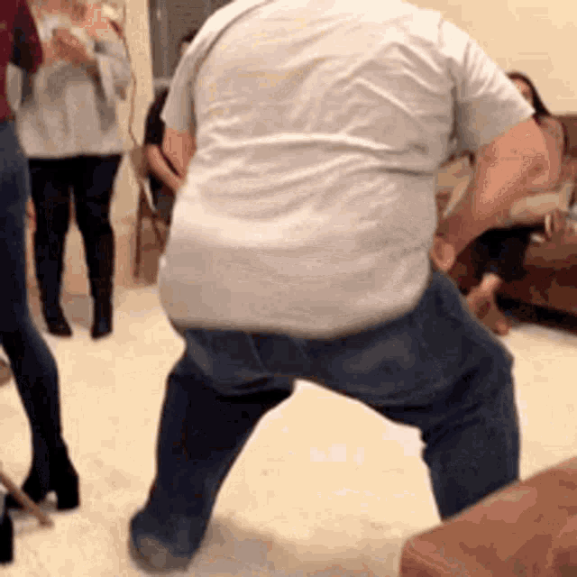 a man in a white shirt and blue jeans is dancing in a room .