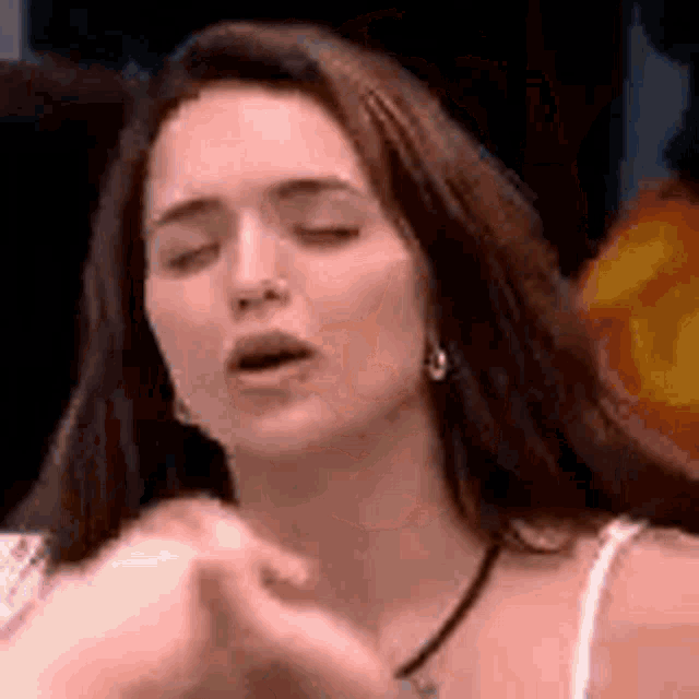 a woman is making a funny face with her eyes closed .