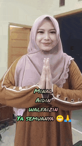 a woman wearing a hijab says minal aidin walfaizin ya semunya