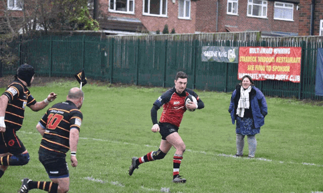 a man running with a rugby ball in front of a sign that says " multi award winning "