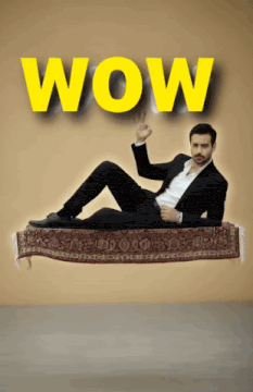 a man in a suit is laying on a flying rug with the word wow behind him