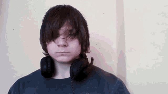 a young man wearing headphones and a black shirt looks at the camera