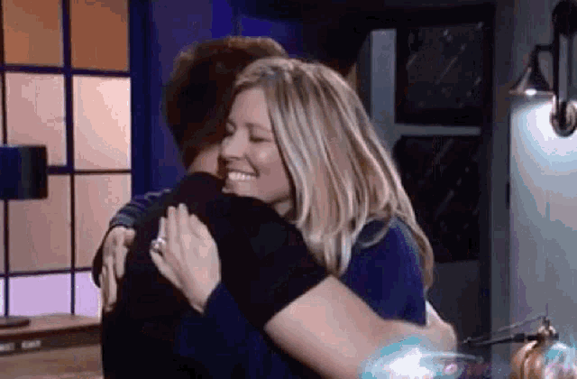 a woman is hugging a man in a room .