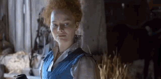 a woman with red hair is wearing a blue vest .
