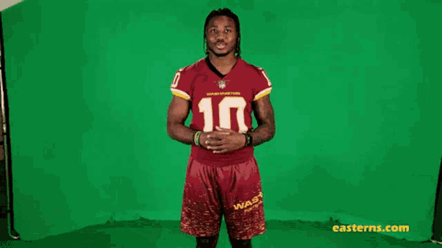 a man in a washington redskins jersey and shorts stands in front of a green screen