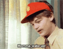 a boy wearing a red hat says " momma wake up "