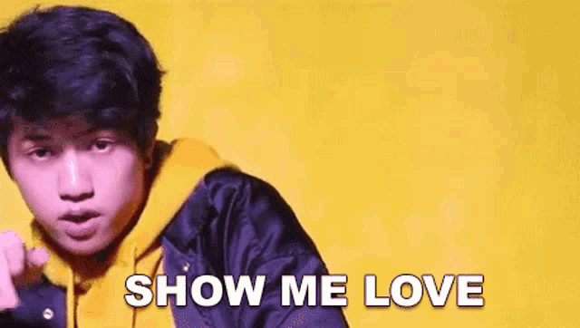 a young man is standing in front of a yellow background with the words `` show me love '' .