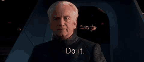 a man in a suit is sitting in a chair with the words `` do it '' written on his face .
