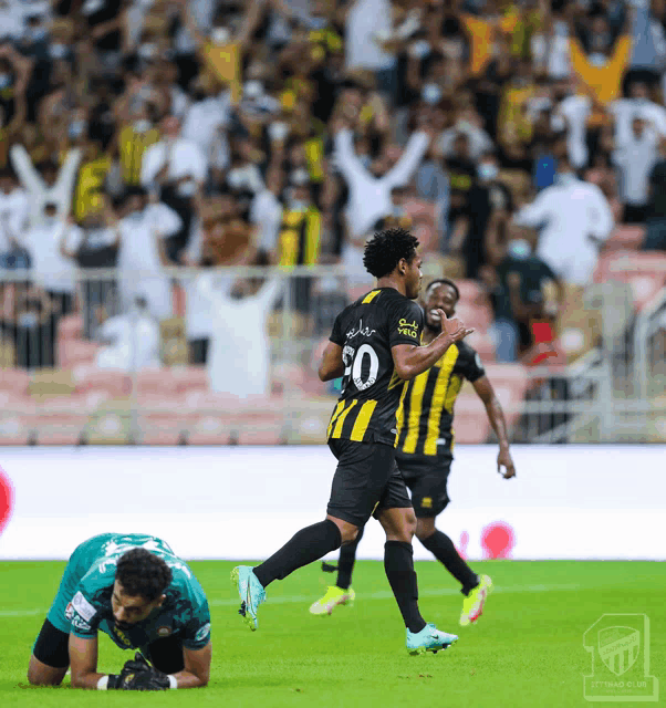 a soccer player wearing a black and yellow jersey with the number 30 on it