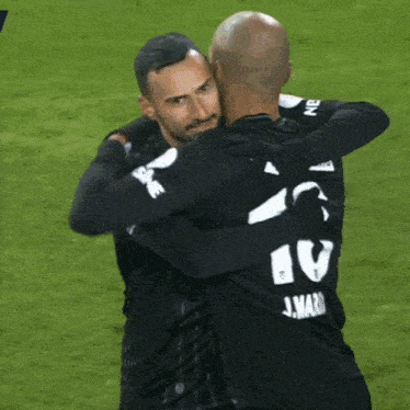 two soccer players wearing beko jerseys are hugging on the field