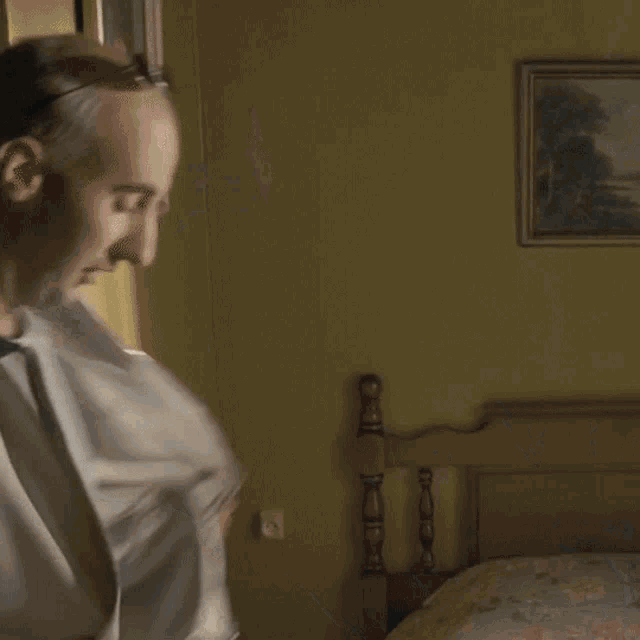 a man wearing sunglasses stands in front of a bed in a room