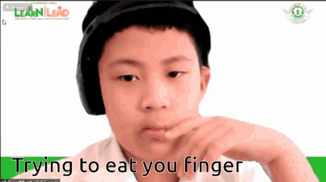 a boy wearing headphones and a hat is trying to eat your finger