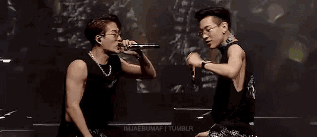 a couple of men are standing next to each other on a stage .