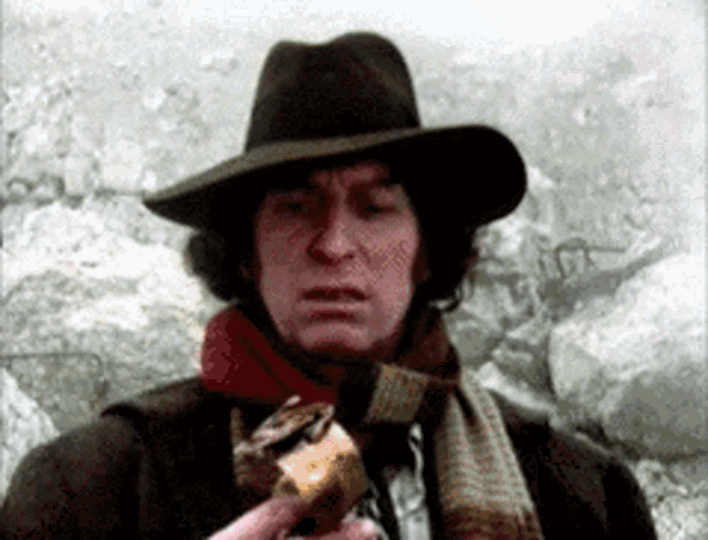 a man wearing a hat and scarf is holding a piece of bread