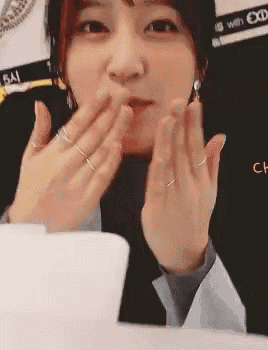 a close up of a woman 's face with her hands in front of her mouth .