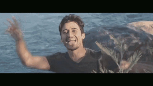 a man in a black shirt is sticking his tongue out in the water .