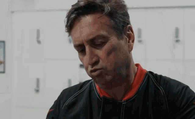 a man in a black and red shirt is looking down