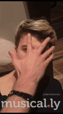 a person covering another person 's face with their hand with the words musically written on the bottom