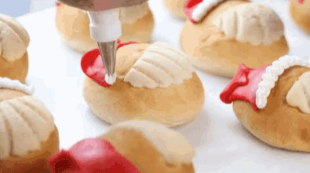 a pastry being decorated with white frosting and red icing