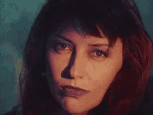 a close up of a woman 's face with red hair and a blue background .
